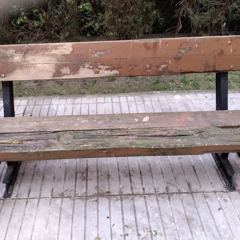 Banco de madera de exterior antes de tratarlo, con la pintura levantada y la madera castigada