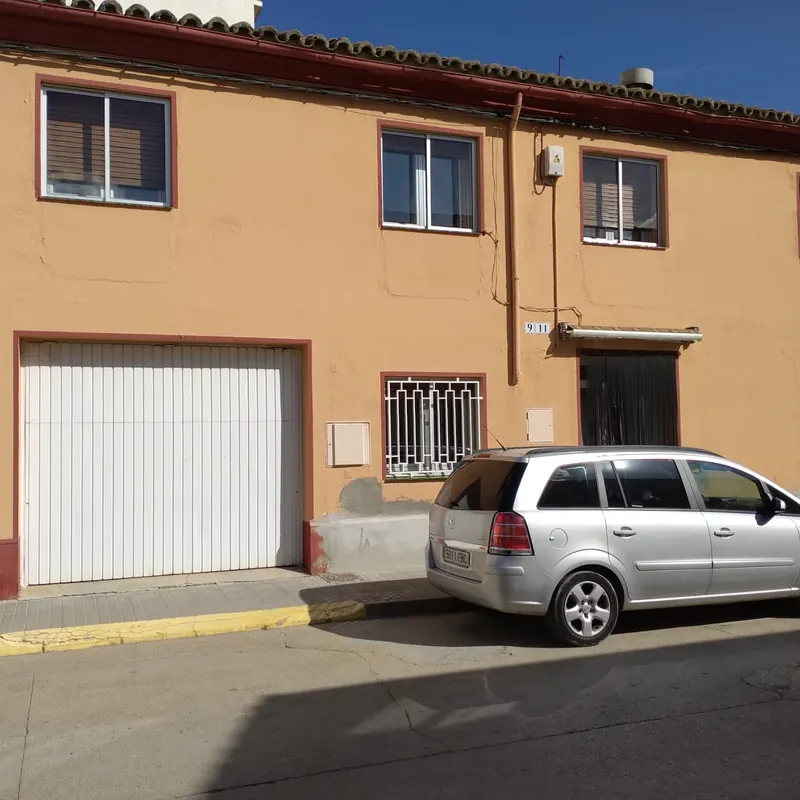 Fachada de vivienda antes de pintar, en color ocre y con el zócalo desgastado