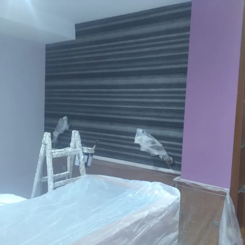Dormitorio antes de pintar: pared de cabecera con papel pintado de rayas oscuras y pared lateral lila