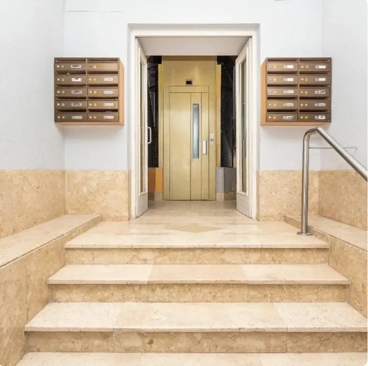 Portal de un edificio de viviendas con buzones, escalera de mármol y ascensor