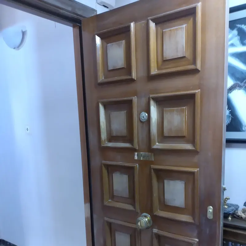 Puerta de entrada de madera con paneles antes de barnizar, con el acabado apagado