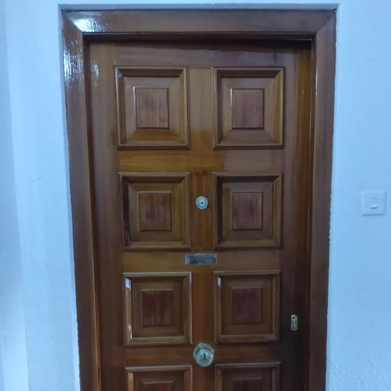 Puerta de entrada de madera con paneles después de barnizar, con acabado brillante